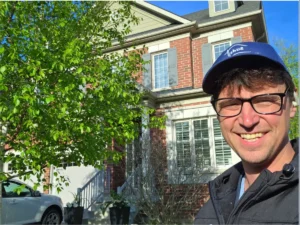 A friendly professional window washer from SUDS Window and Eaves Cleaning standing in front of a residential home before an interior and exterior cleaning service in Toronto.