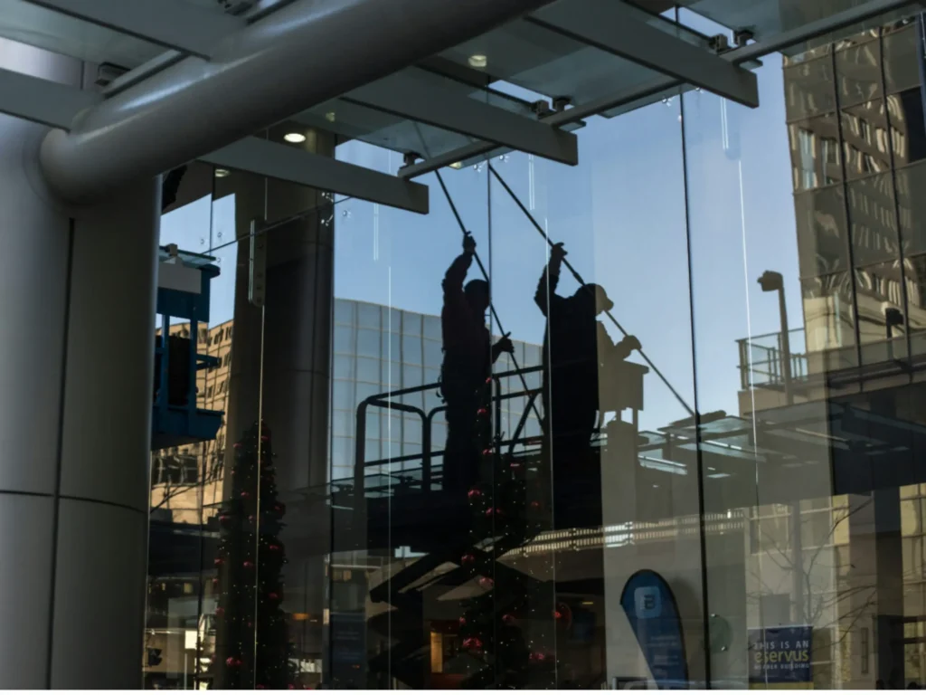 Professional window cleaners on a lift washing a large commercial glass facade, highlighting how to avoid 5 common window cleaning mistakes you might be making.