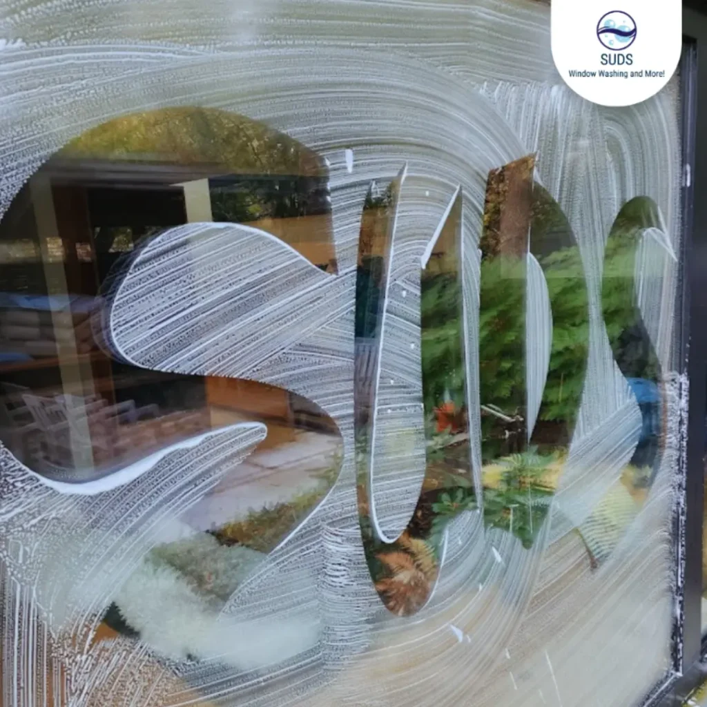Soapy residential window glass featuring the SUDS brand name, highlighting home maintenance and eavestrough clog prevention services in Toronto.