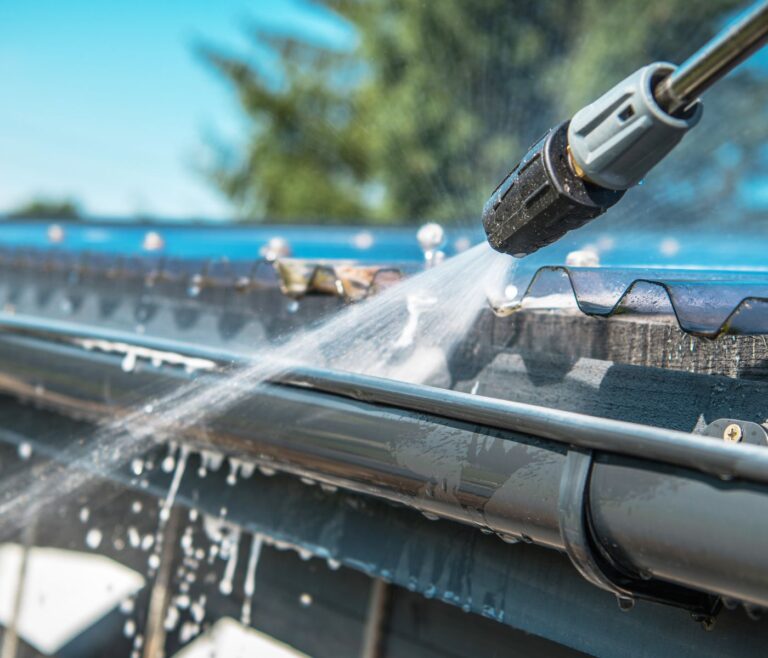 Gutter being flushed with water during residential eavestrough cleaning.