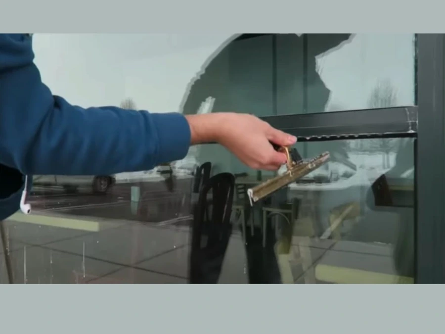 Professional window cleaner using a squeegee to clean exterior glass in Toronto.